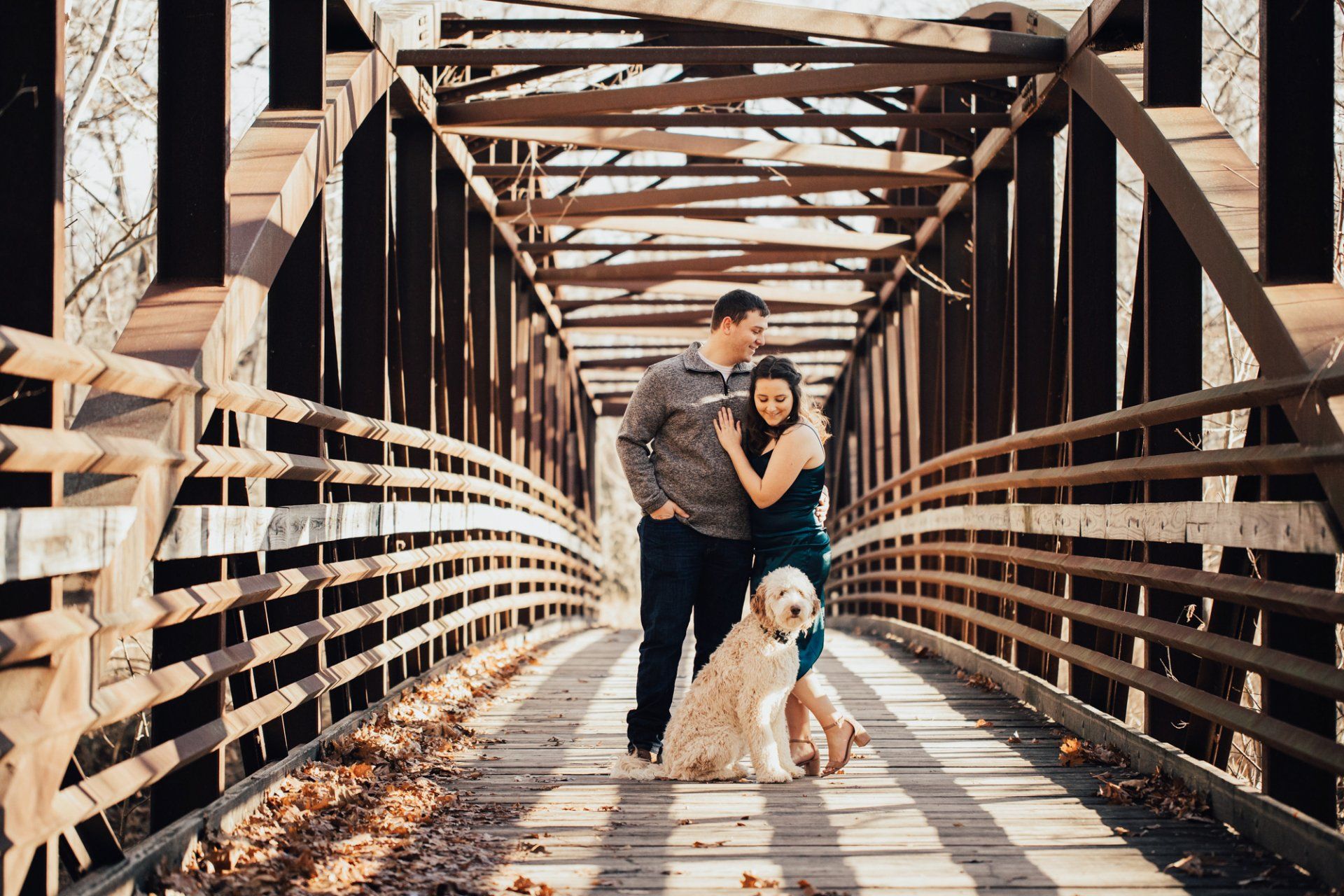Man kisses his fiance on the forehead as they stand with their dog