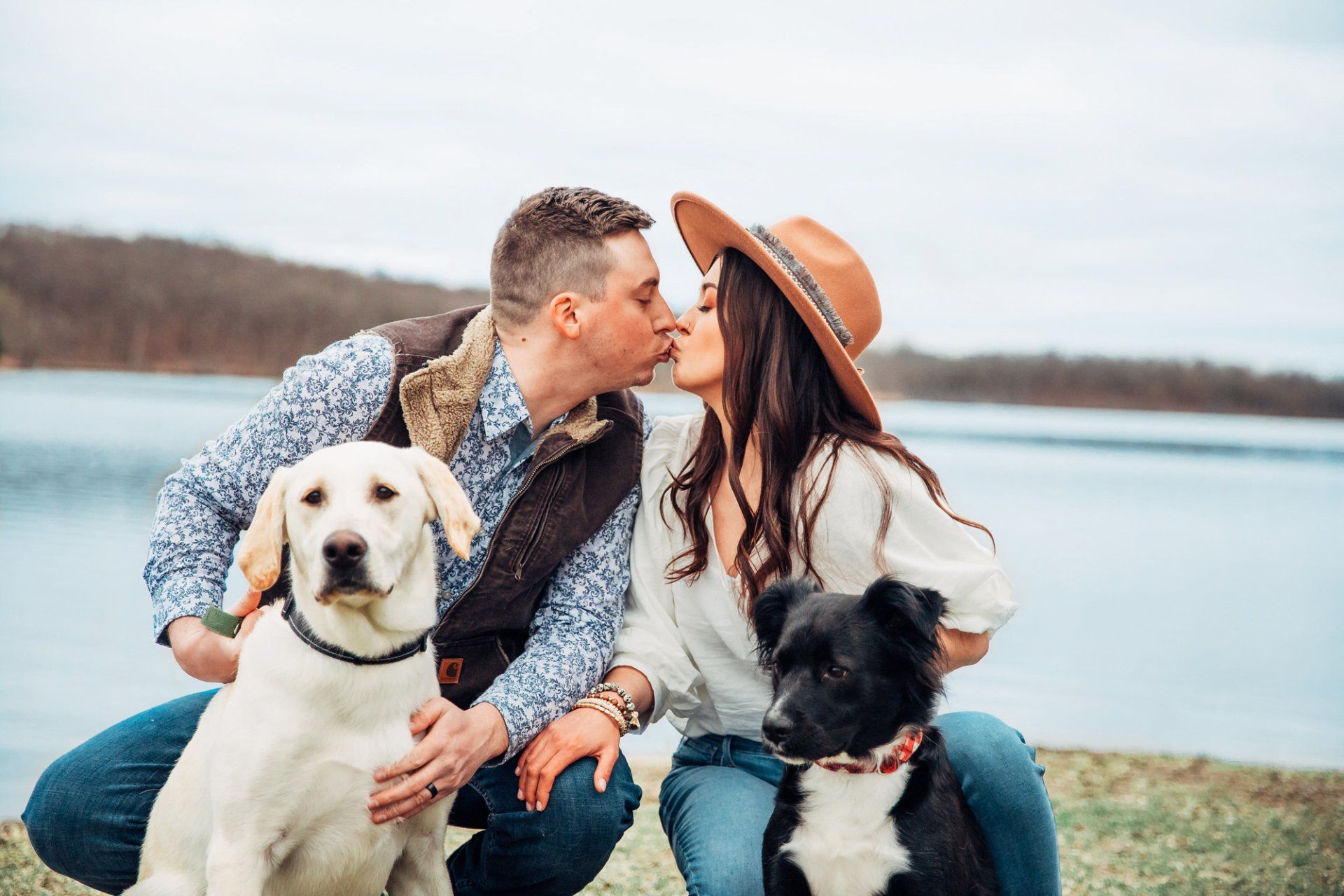 Engaged couple kiss as they pose with their dogs