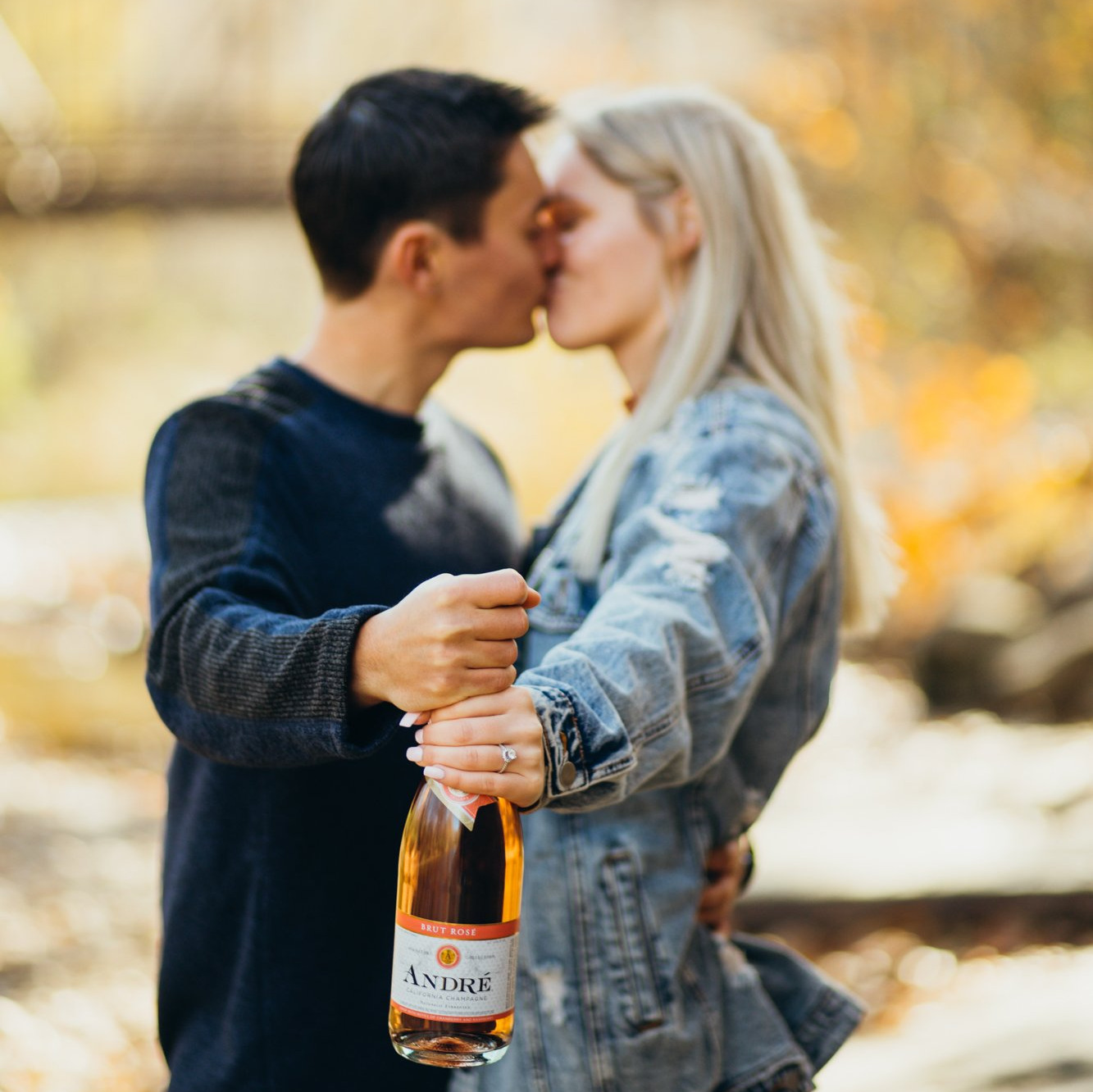 Engaged couple kiss as they hold champagne