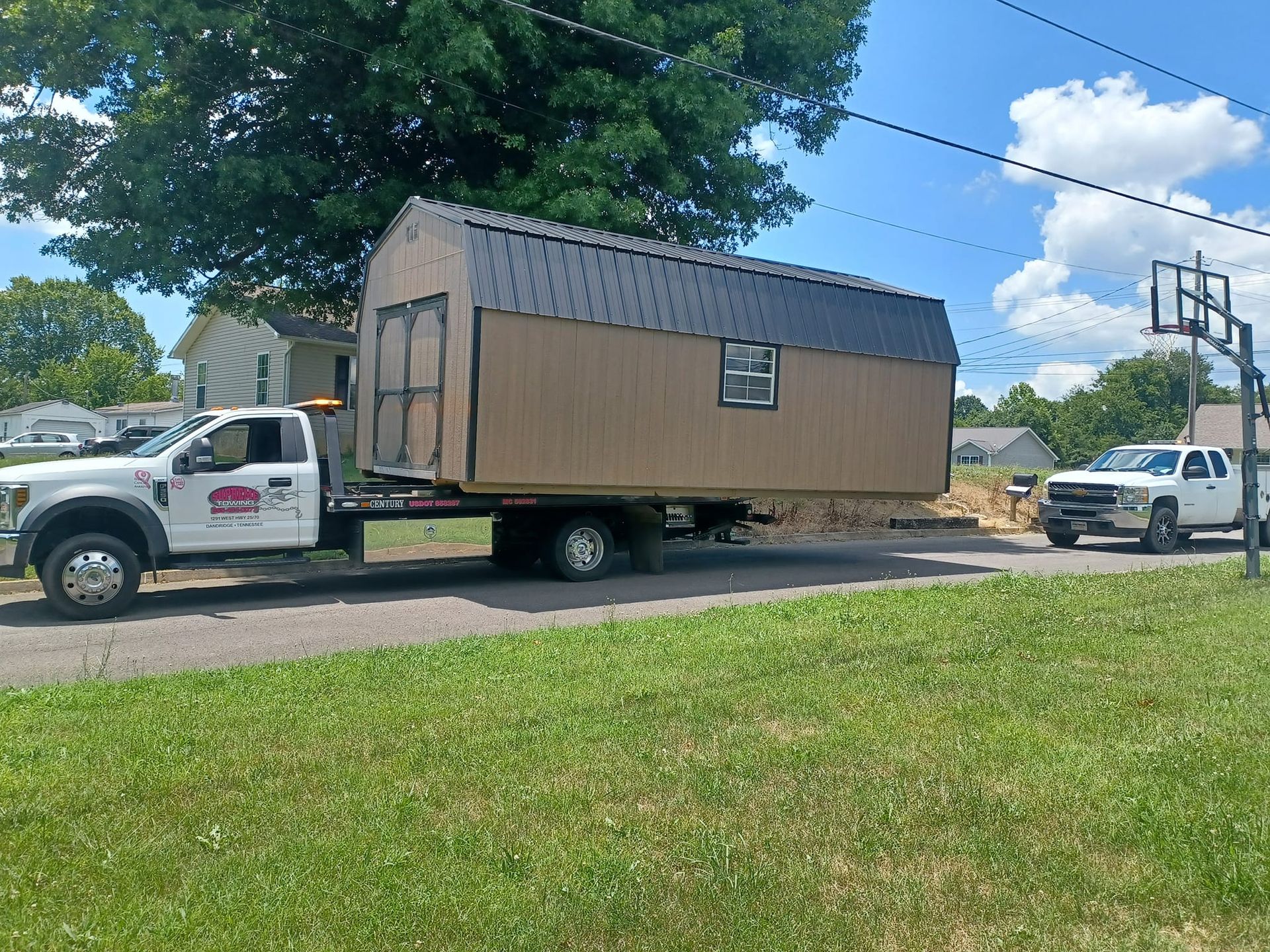 A truck is towing a shed down a road.
