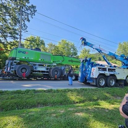 A man is standing next to a tow truck with a crane attached to it.