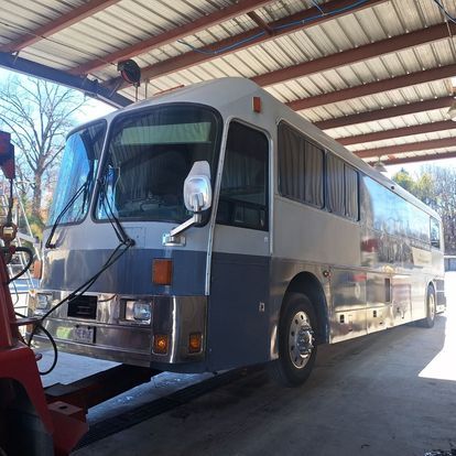 A blue and white bus is parked under a roof