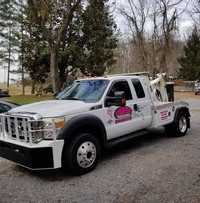 A white tow truck is parked on the side of the road.