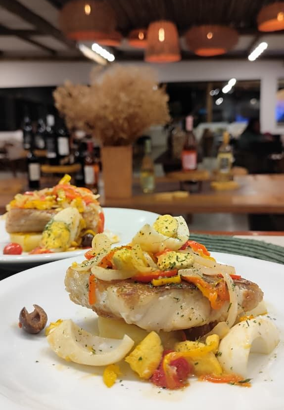 Prato de comida com carne assada, molho, purê de batatas e raminho de alecrim.