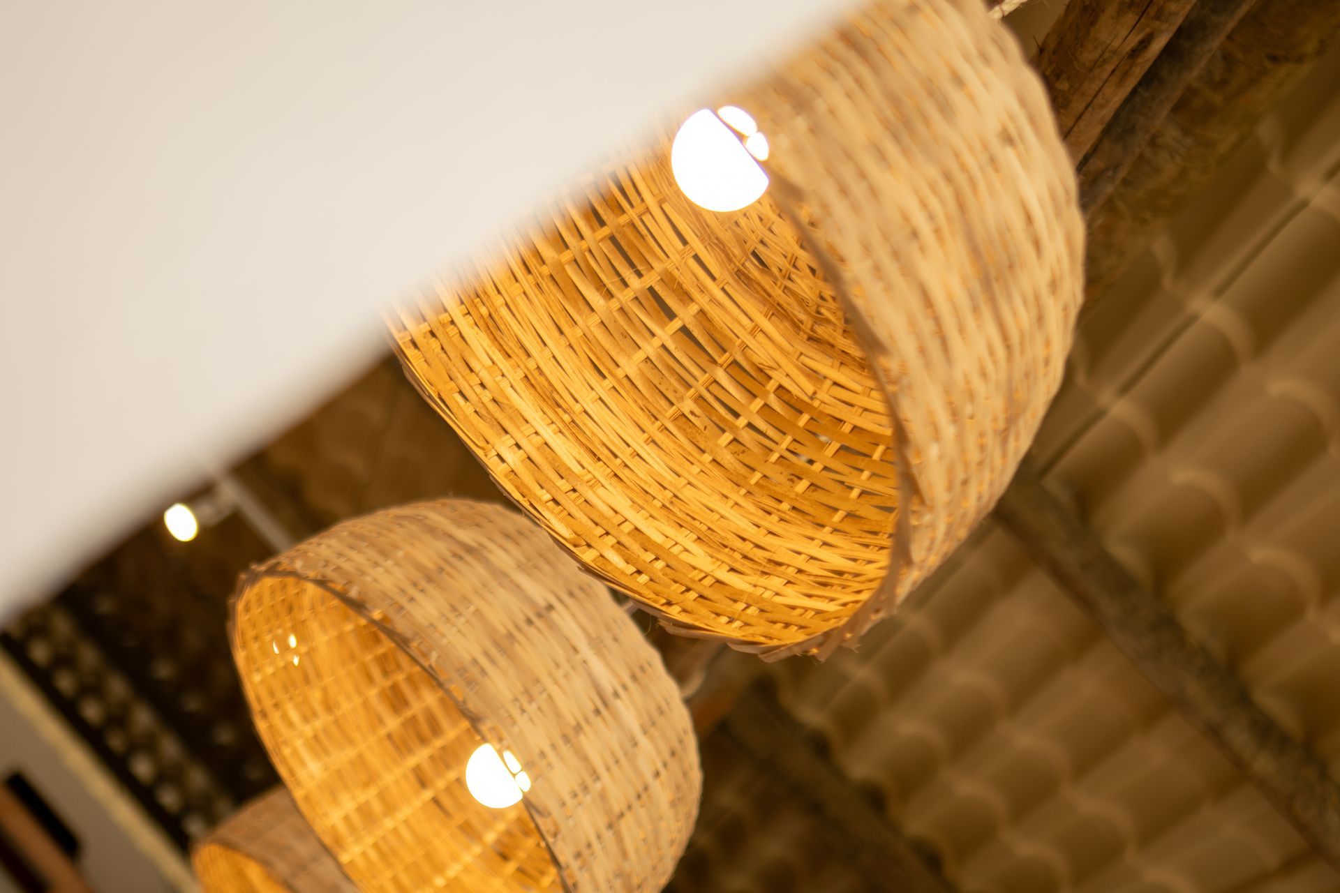 Luminárias pendentes de cesta trançada penduradas em um teto rústico, brilho aconchegante.