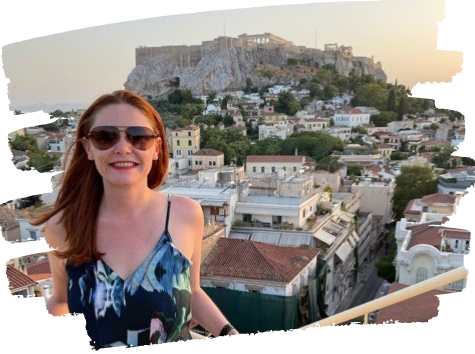 Woman on a rooftop smiles at the camera, with the Acropolis in Athens in the background.