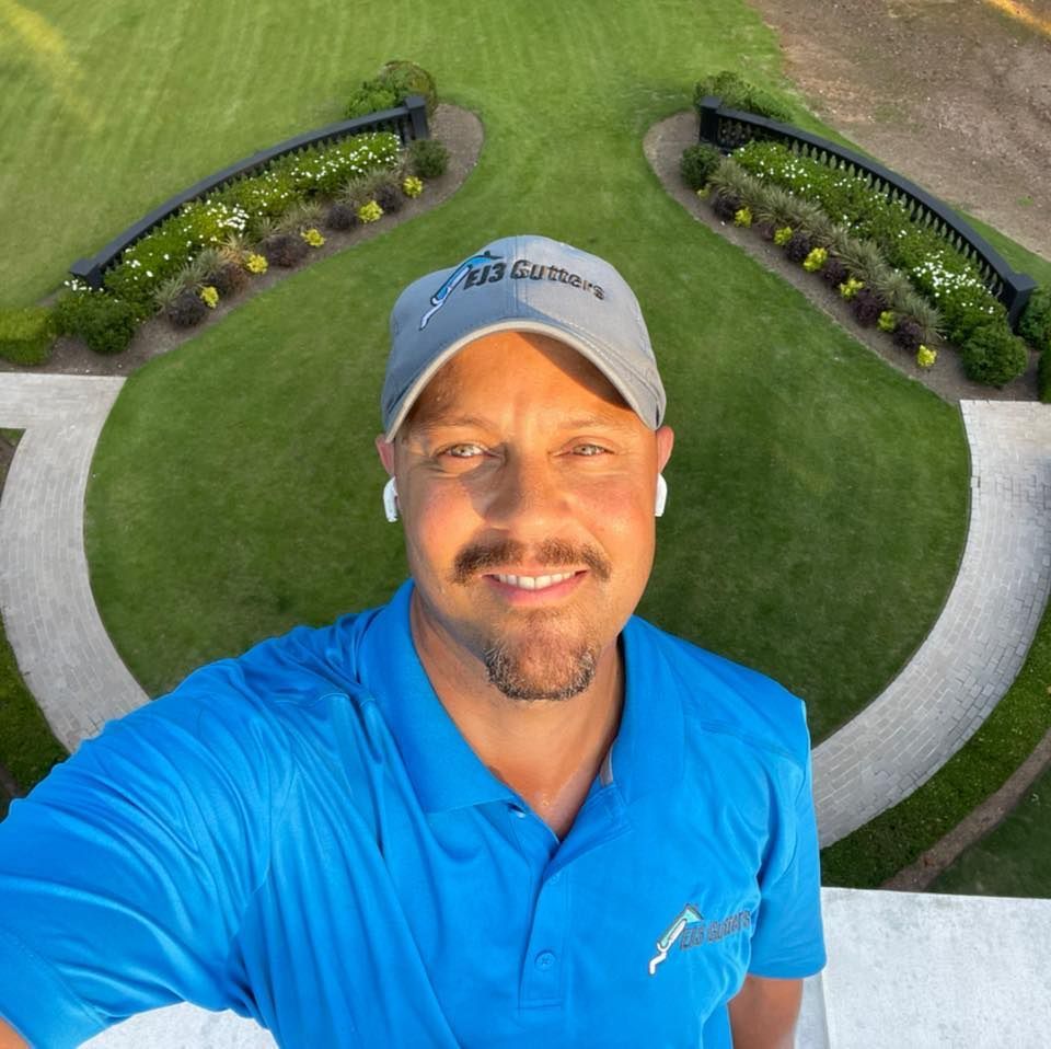 A man is sitting on top of a roof overlooking a forest.