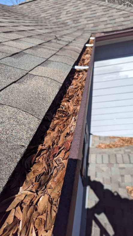 A gutter filled with leaves on the side of a house.