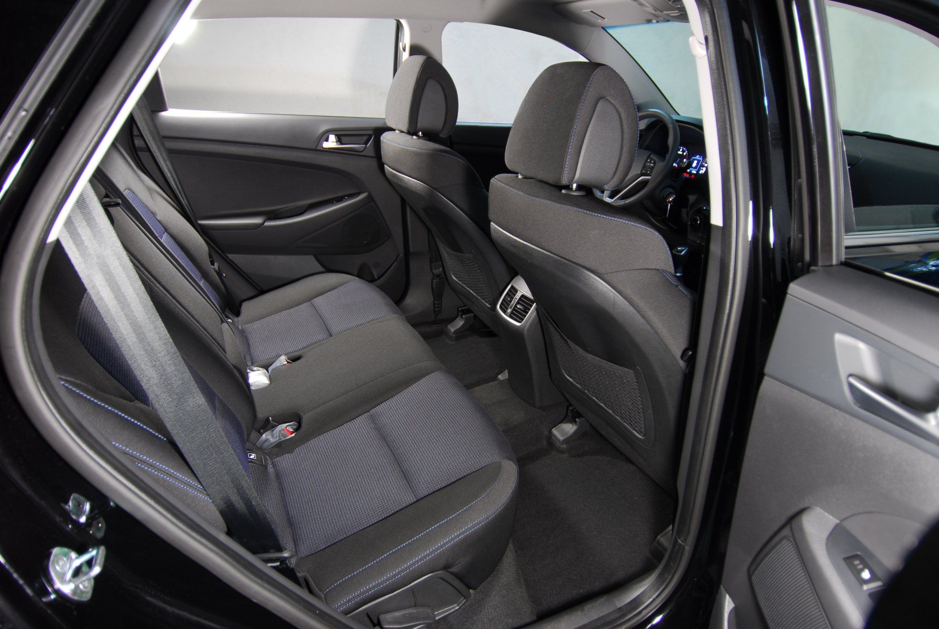 The back seat of a black car with the door open.