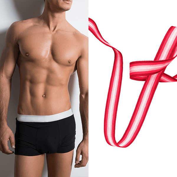 A shirtless man in black shorts next to a red and white ribbon