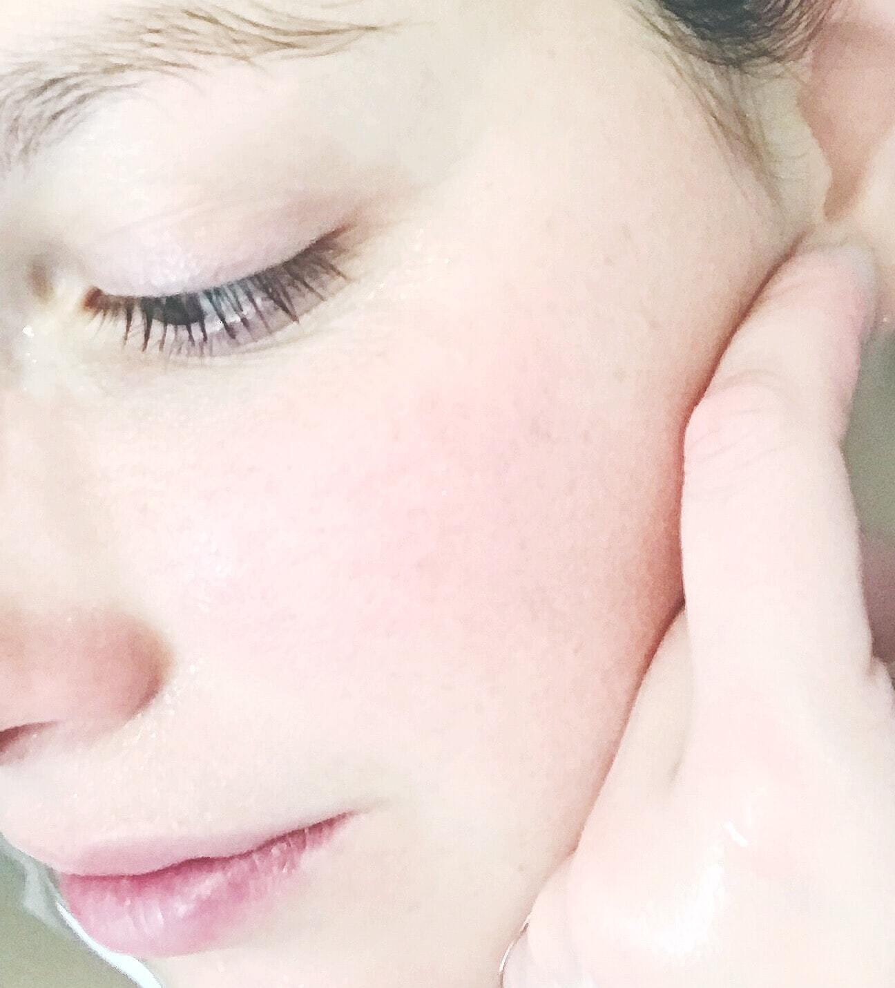A close up of a woman 's face with her hand on her face.