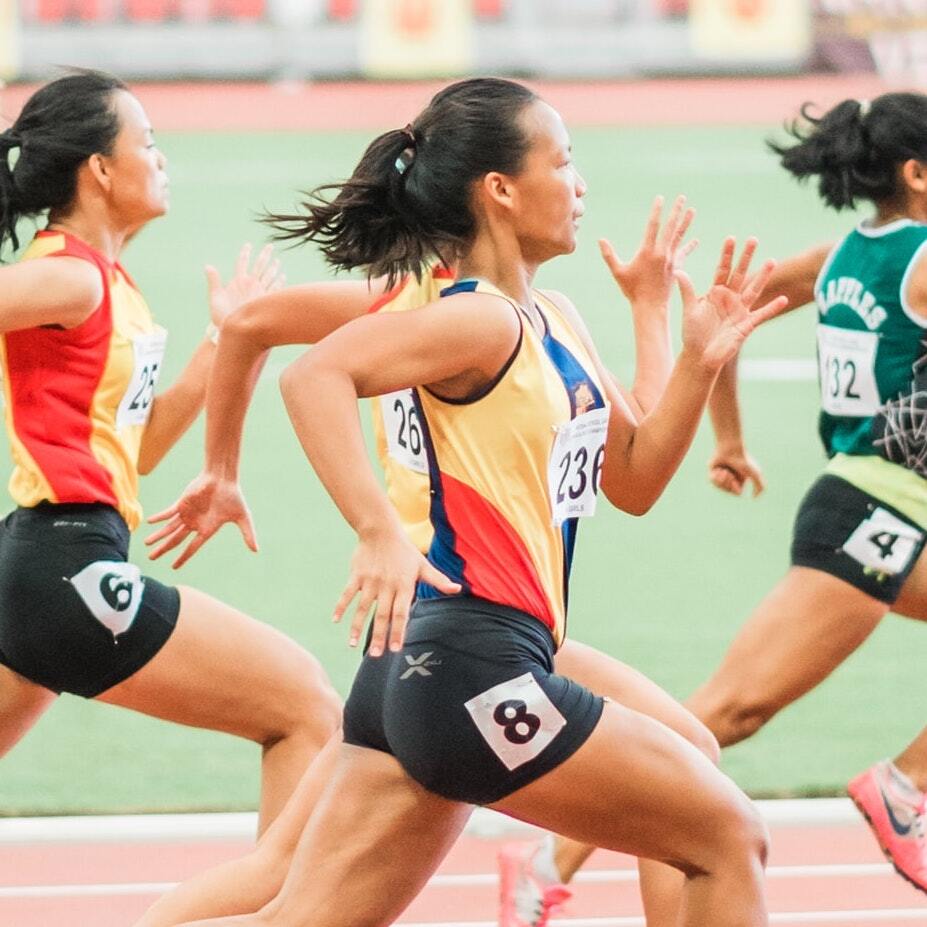 A group of women are running on a track and one has the number 8 on her shorts