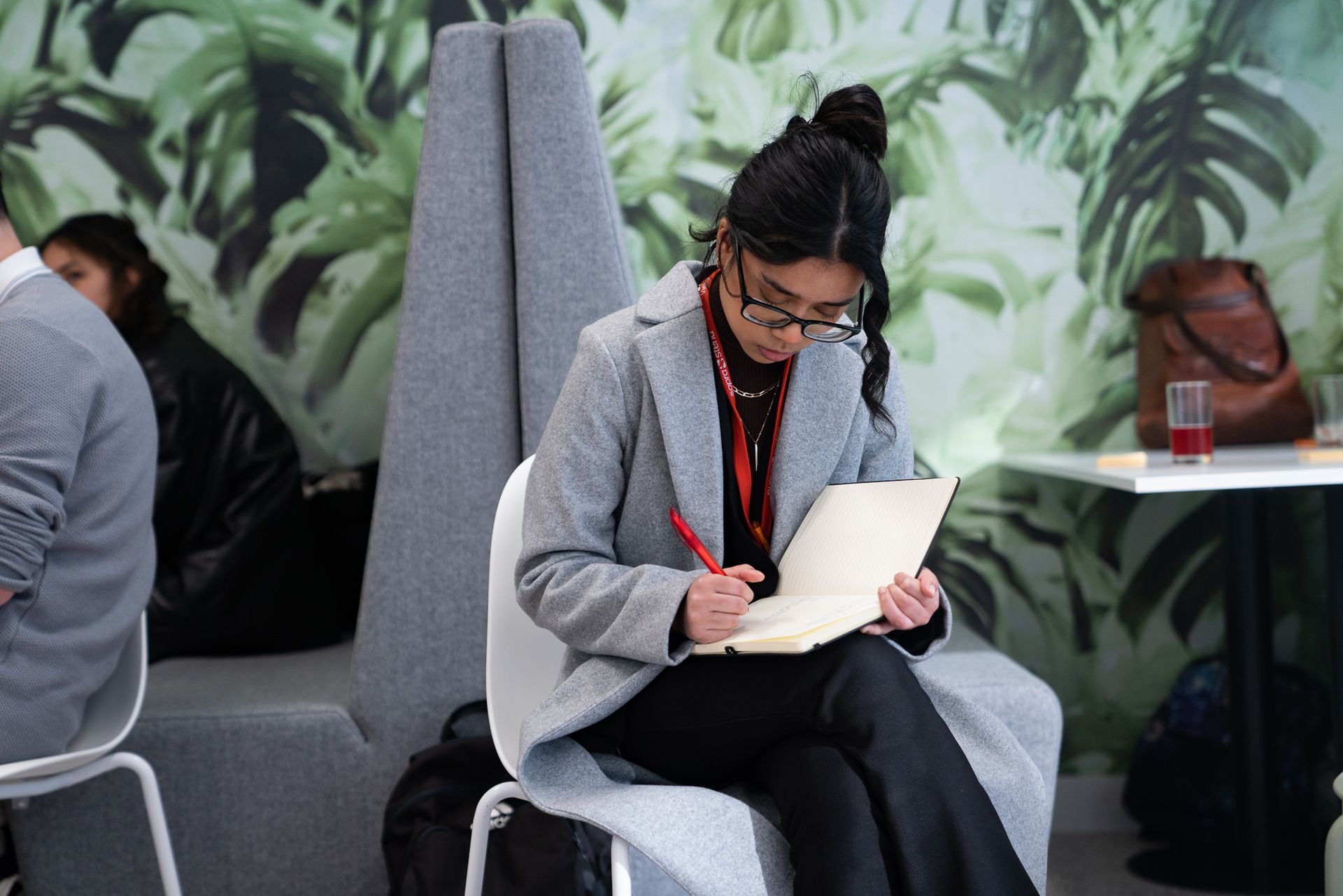A woman is sitting in a chair writing in a notebook.