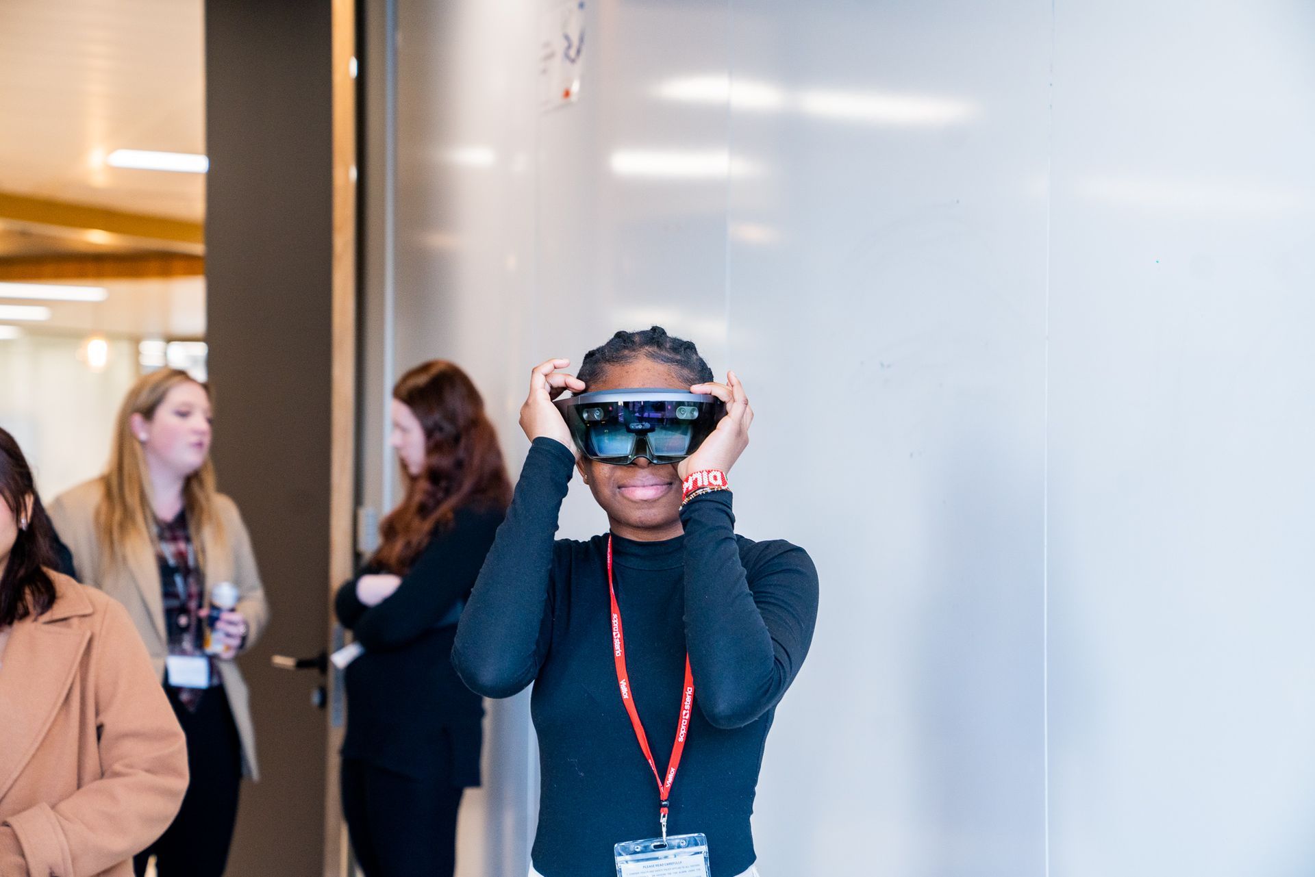 A woman wearing a virtual reality headset is standing in front of a white board.