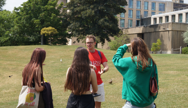 A group of people are standing in a park talking to each other.