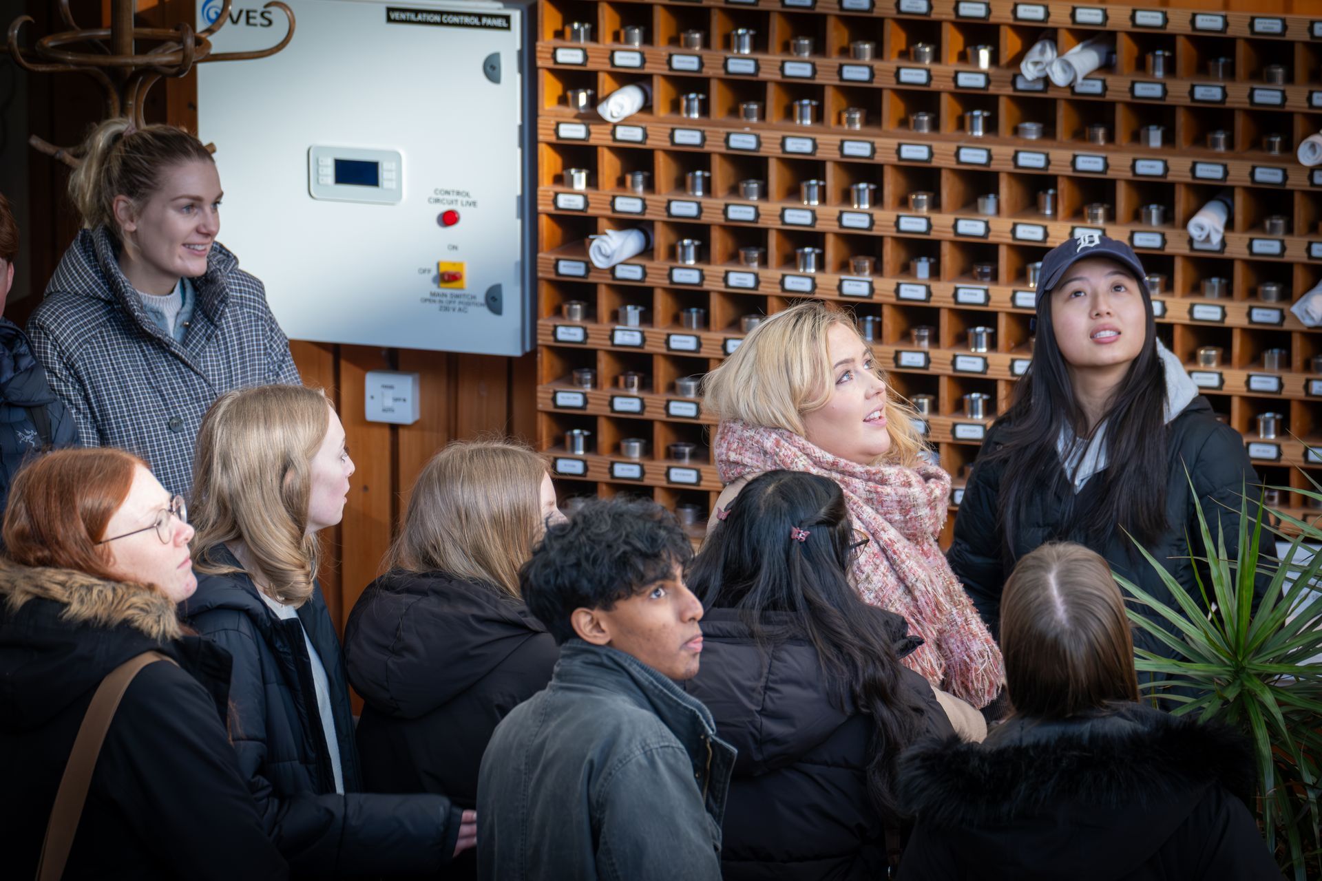 Group of people looking up at a wall of containers, likely on a tour.