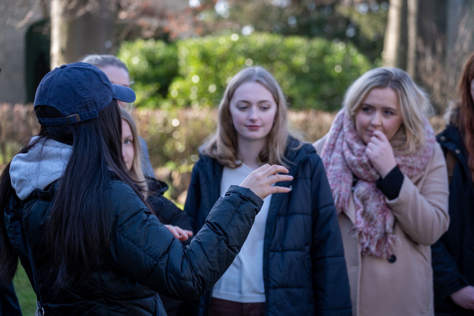 Group of people outside, one woman gestures while others look on.