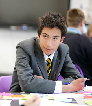 A young man in a suit and tie sits at a table with sticky notes on it