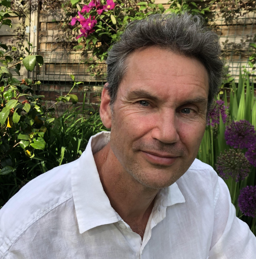 A man in a white shirt is sitting in front of flowers.