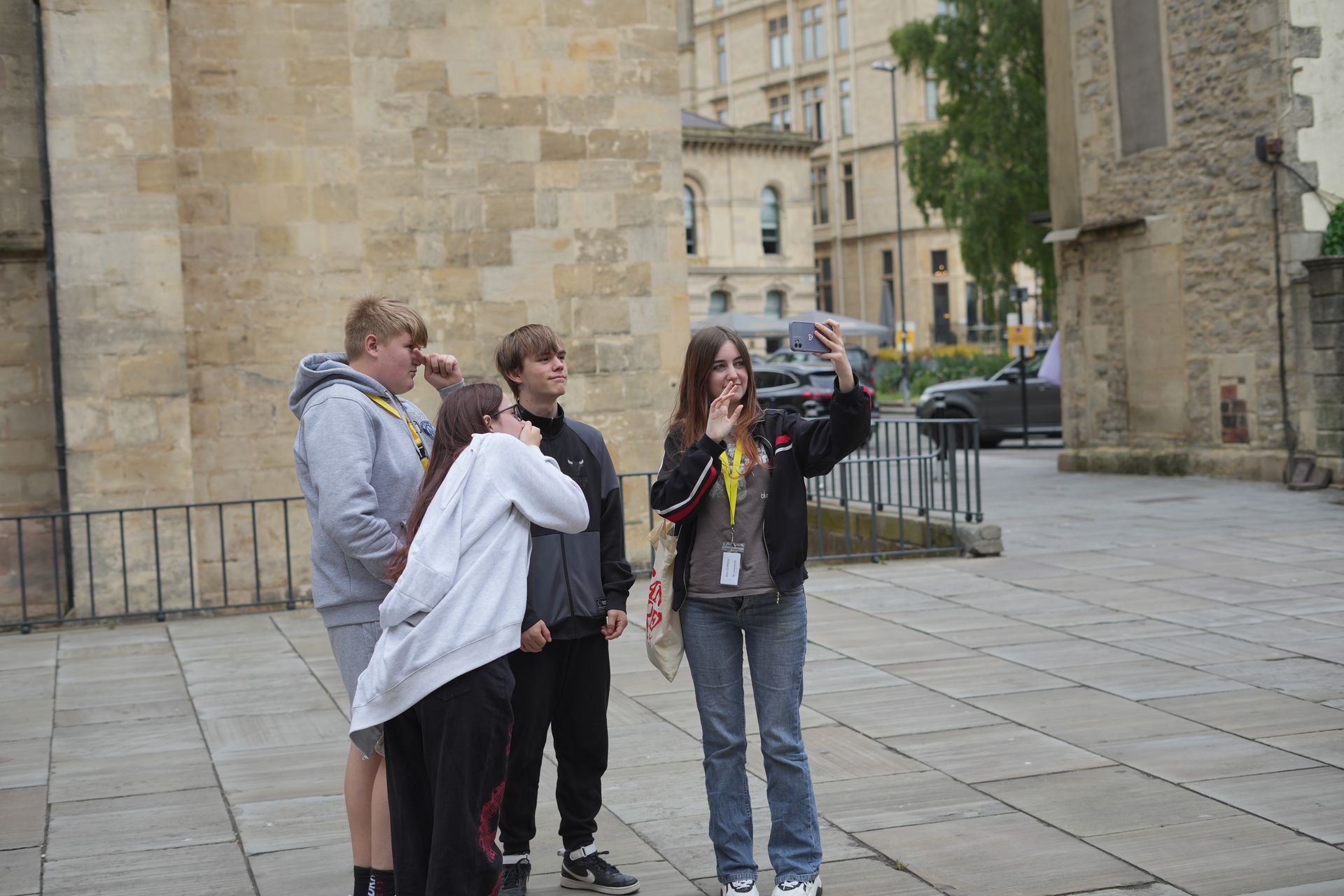 A group of people are standing on a sidewalk in front of a building.