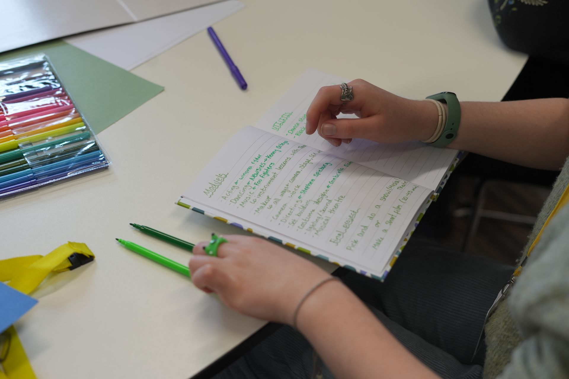 A person is sitting at a table writing in a notebook.