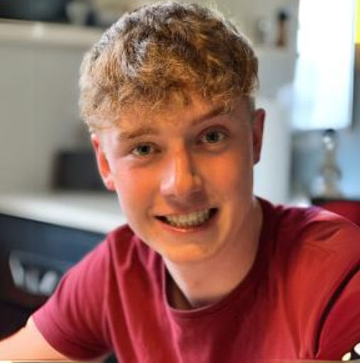 A young man in a red shirt is smiling for the camera