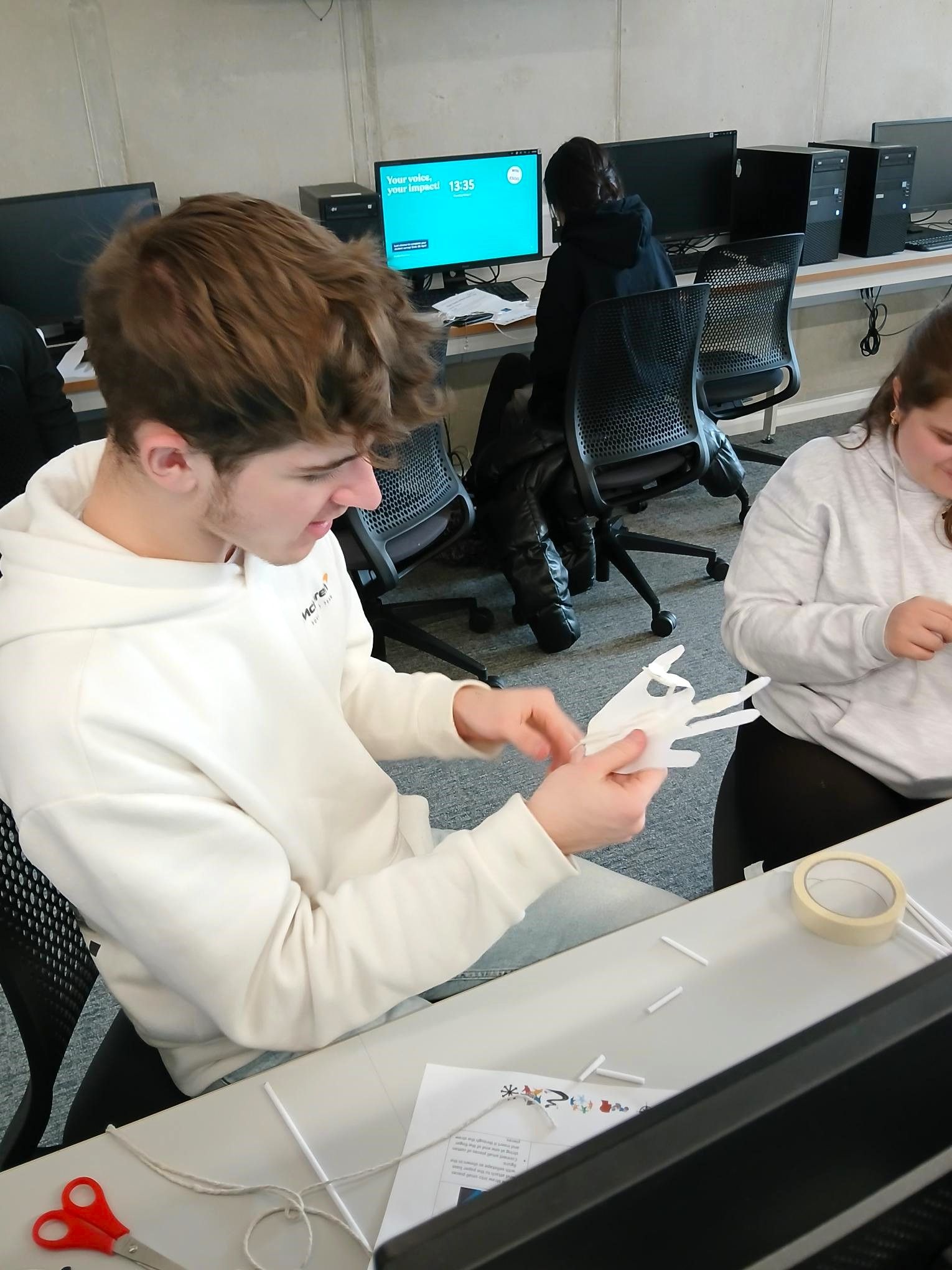 A man and a woman are sitting at a desk in front of a computer.