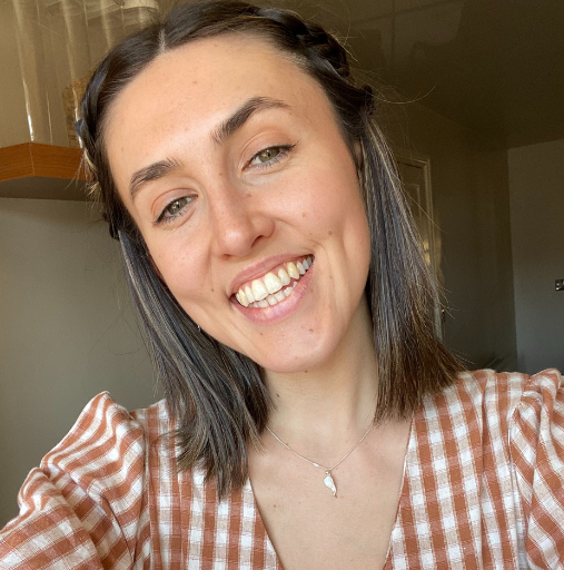 A woman in a plaid shirt is smiling for the camera.