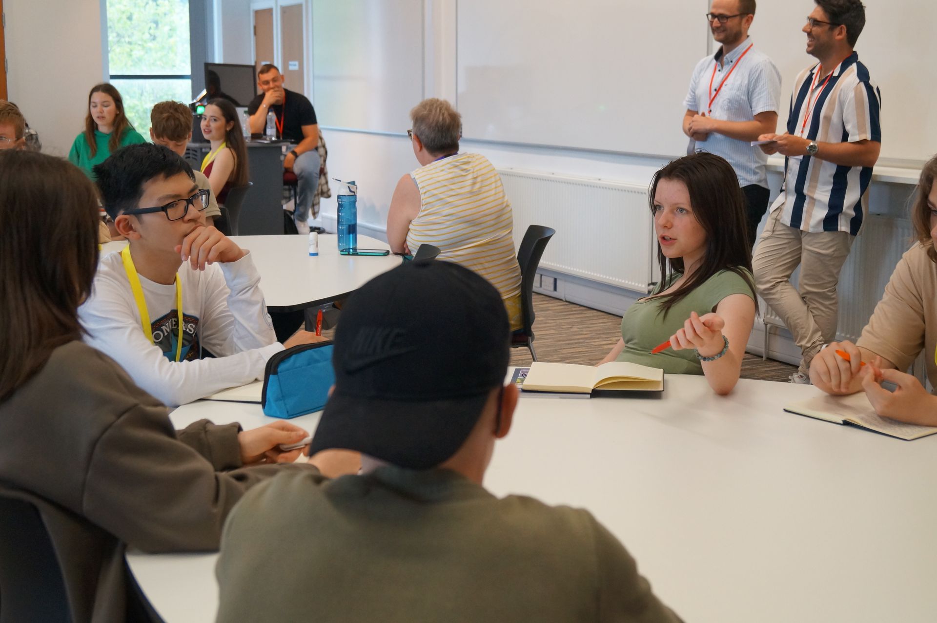 A group of people are sitting around a table in a classroom.