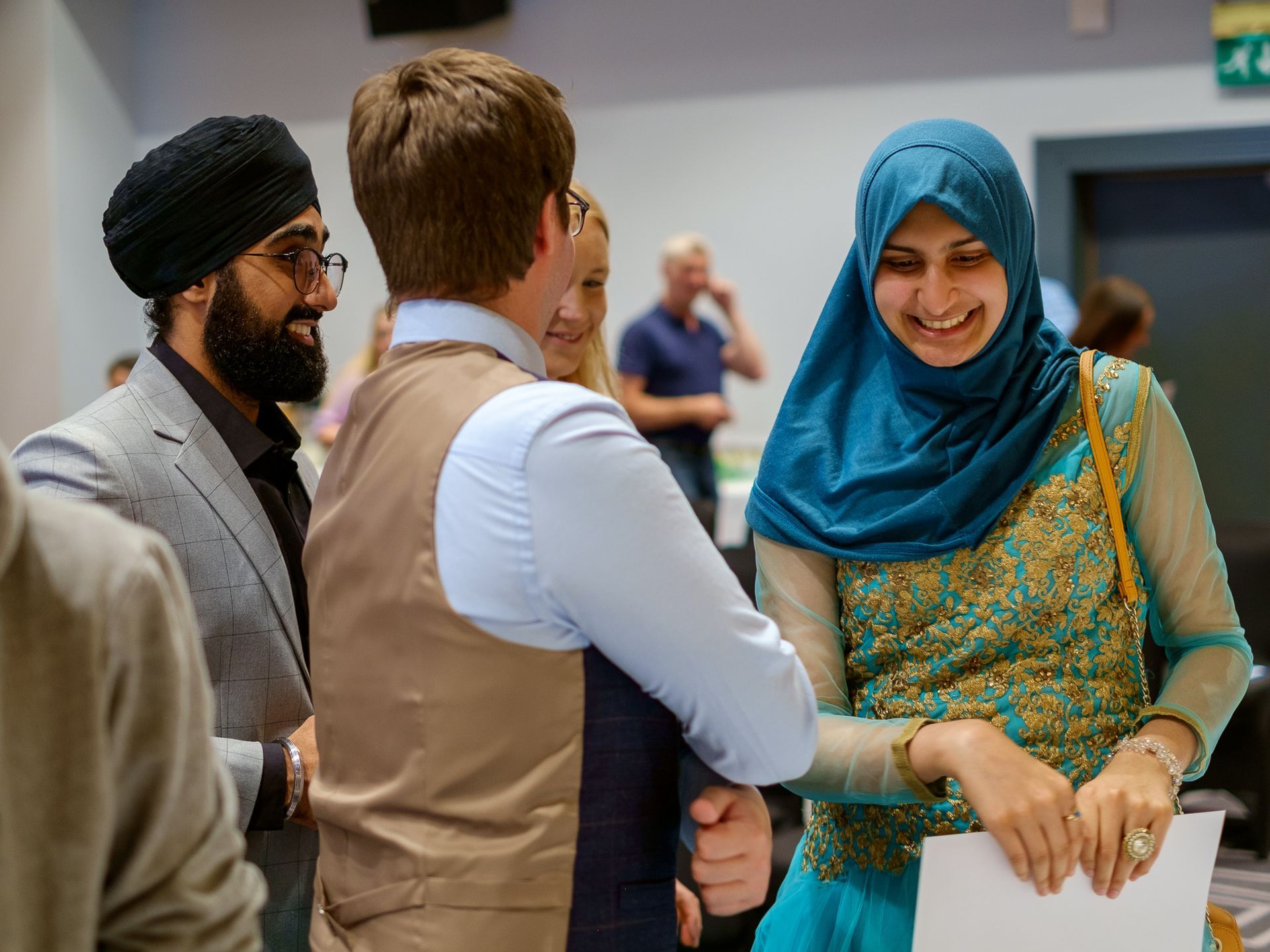 A group of people are standing around talking to each other in a room.