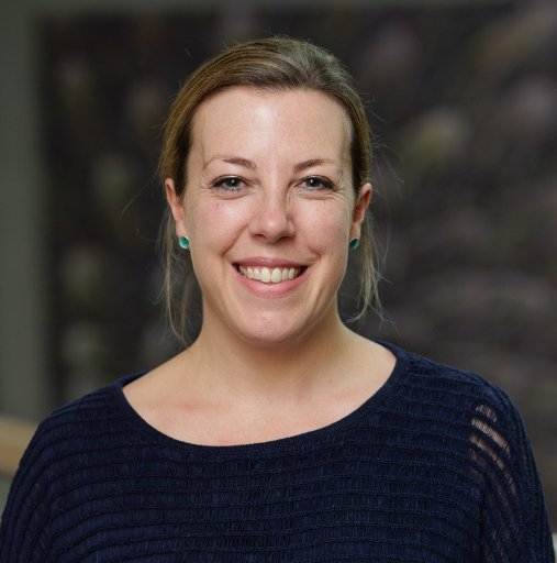 A woman in a blue sweater is smiling for the camera