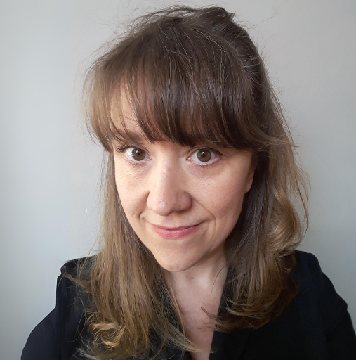 A woman with long hair and bangs is smiling for the camera.