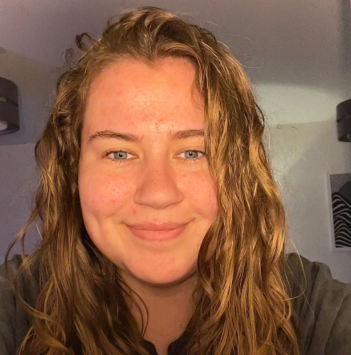 A woman with long brown hair and blue eyes is smiling for the camera.