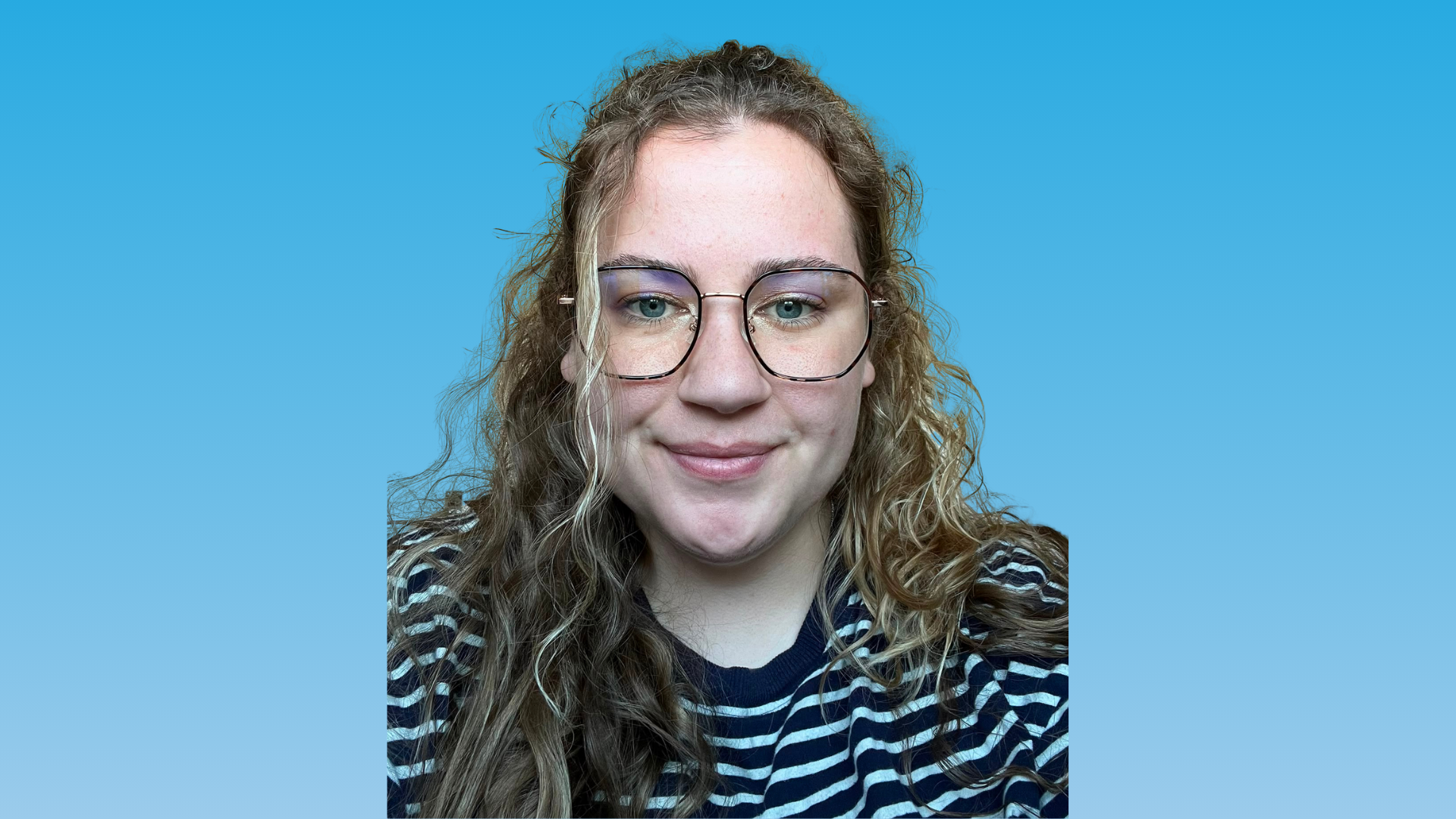 Portrait of a smiling person with curly hair and glasses against a blue background