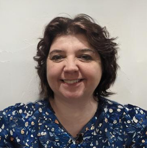 A woman wearing a blue scrub top smiles for the camera