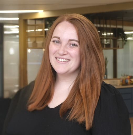 A woman with long red hair is smiling for the camera