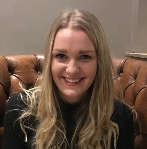 A woman is smiling while sitting on a brown leather couch