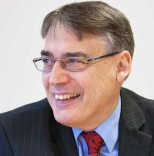 A man in a suit and tie is smiling and wearing glasses