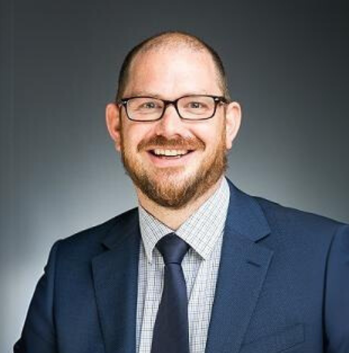 A man in a suit and tie is smiling for the camera.
