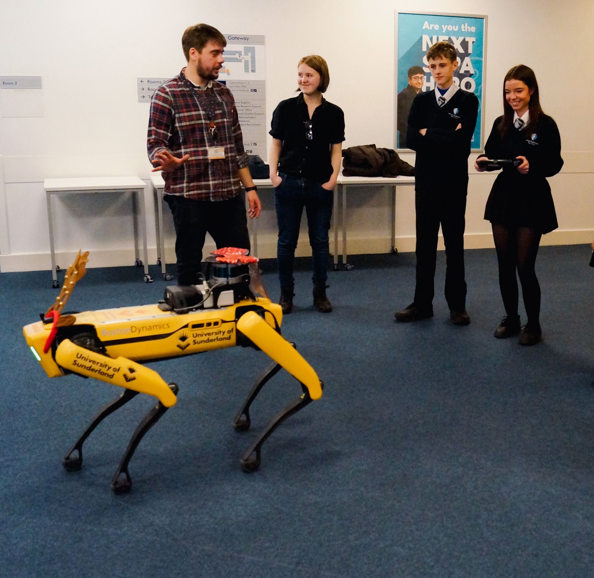 A group of people standing around a yellow robot that says ' next step ' on it