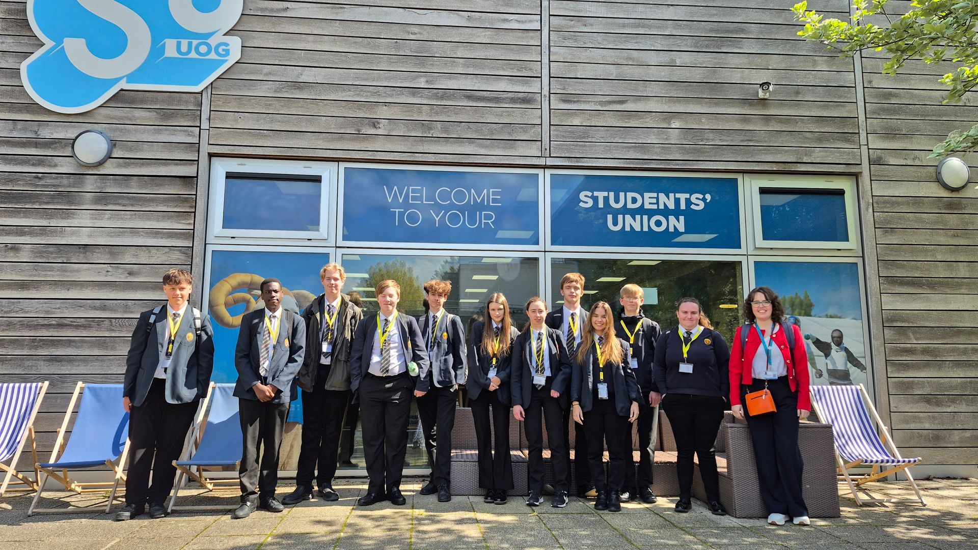 Group of people posing outside the Students' Union building, with stone facade and blue signage.