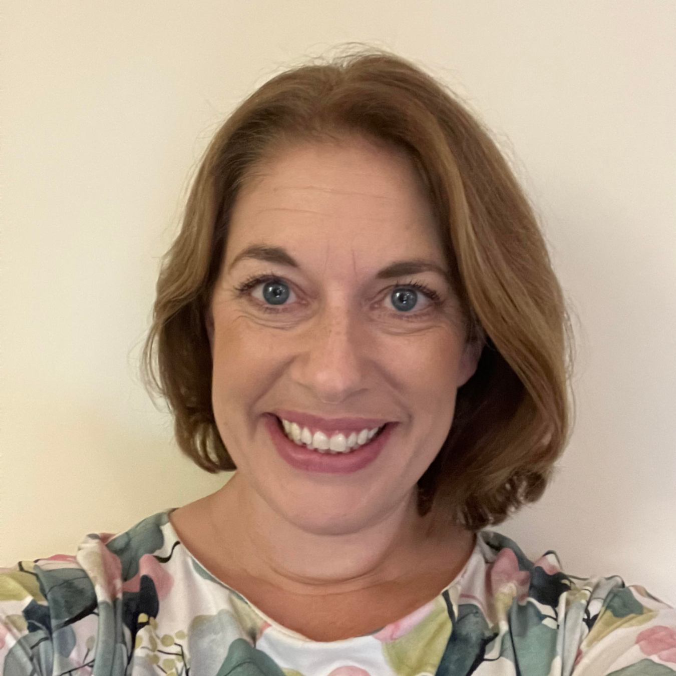 A man with a beard is smiling and wearing a purple shirt