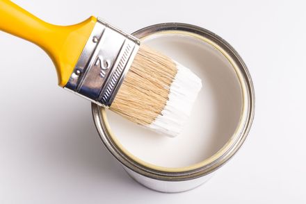 A person is painting a yellow wall with a paint roller.