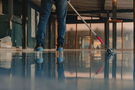 A man is cleaning a concrete floor with a mop.