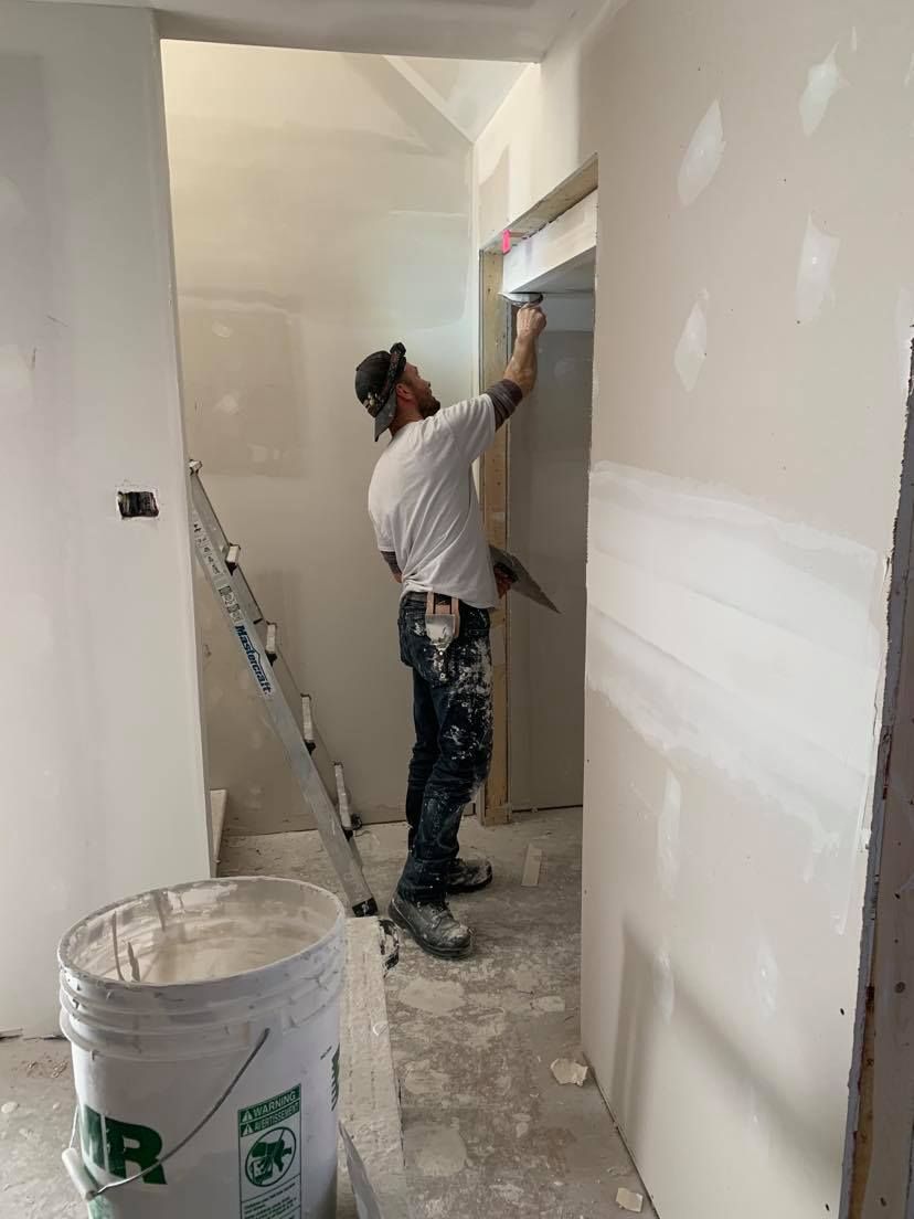 A man is standing in a hallway painting a wall.