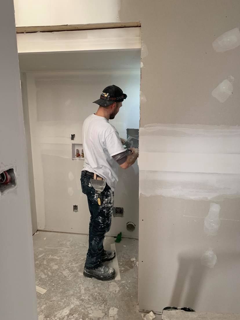 A man is working on a wall in a room.