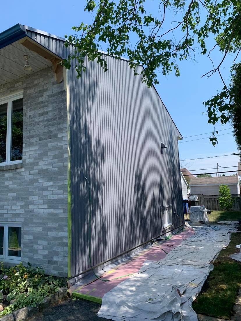 A brick house is being painted in a gray color.