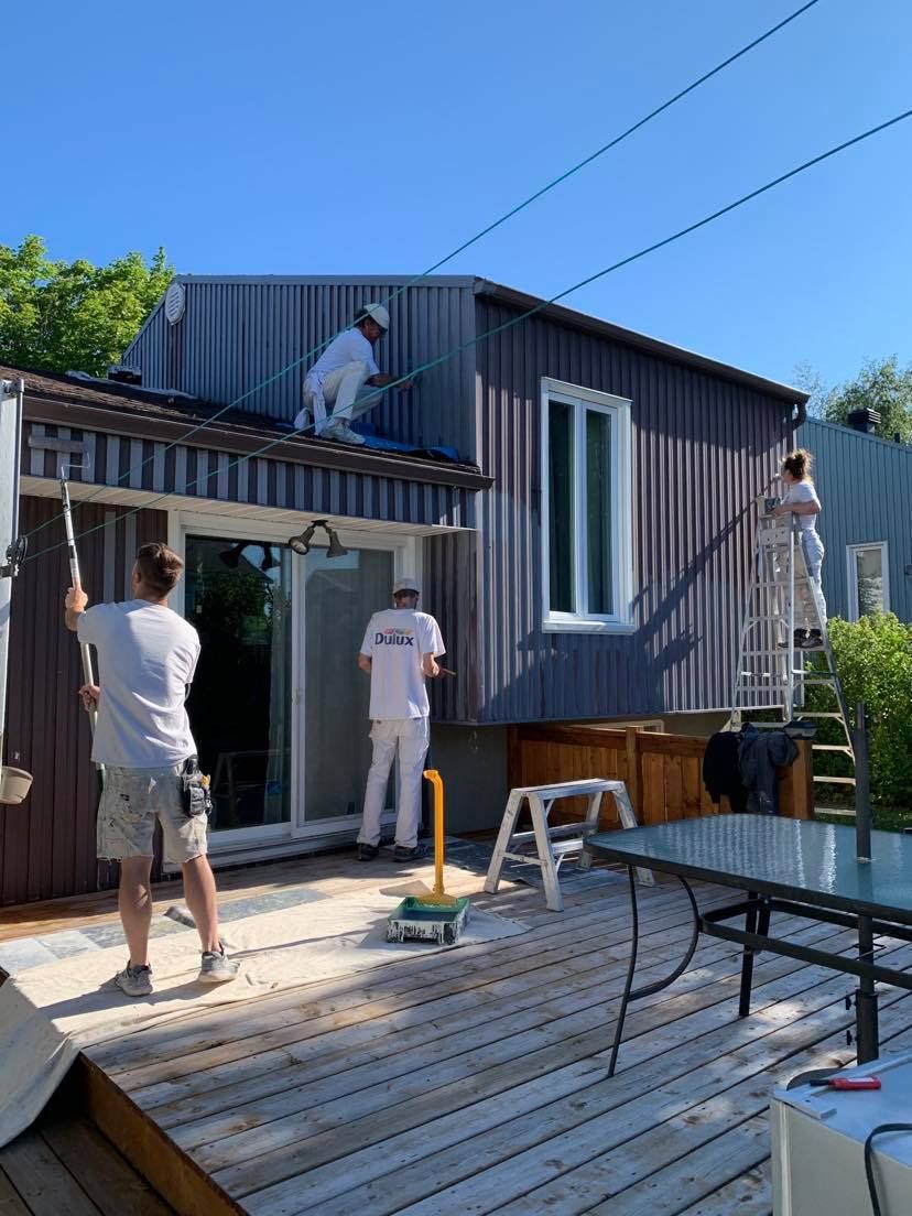 A group of people are painting the side of a house.