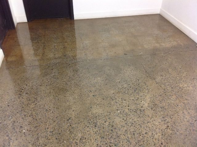 A shiny concrete floor in a room with a door.