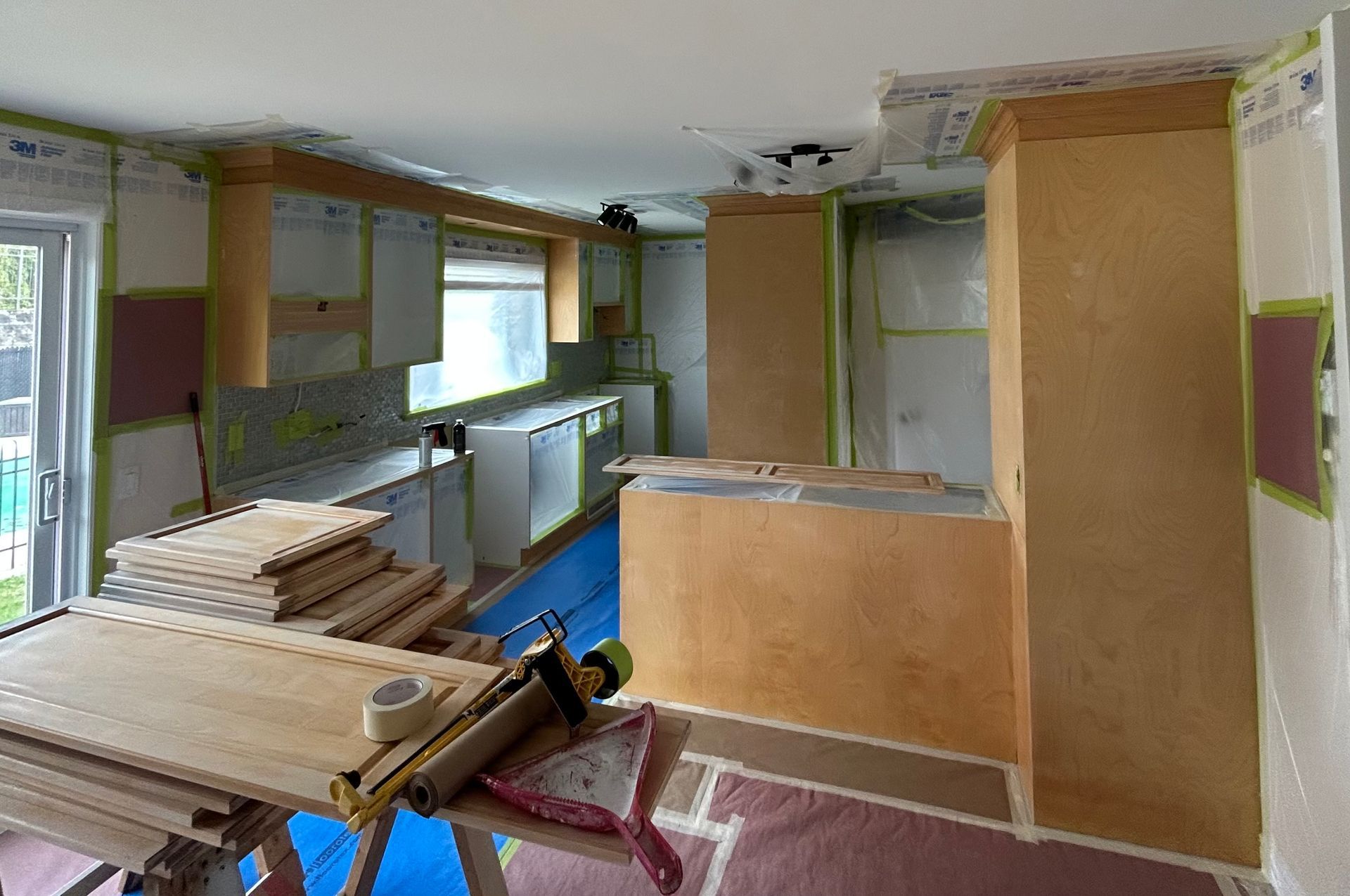 
Une cuisine est en cours de rénovation avec des armoires et des comptoirs en bois.